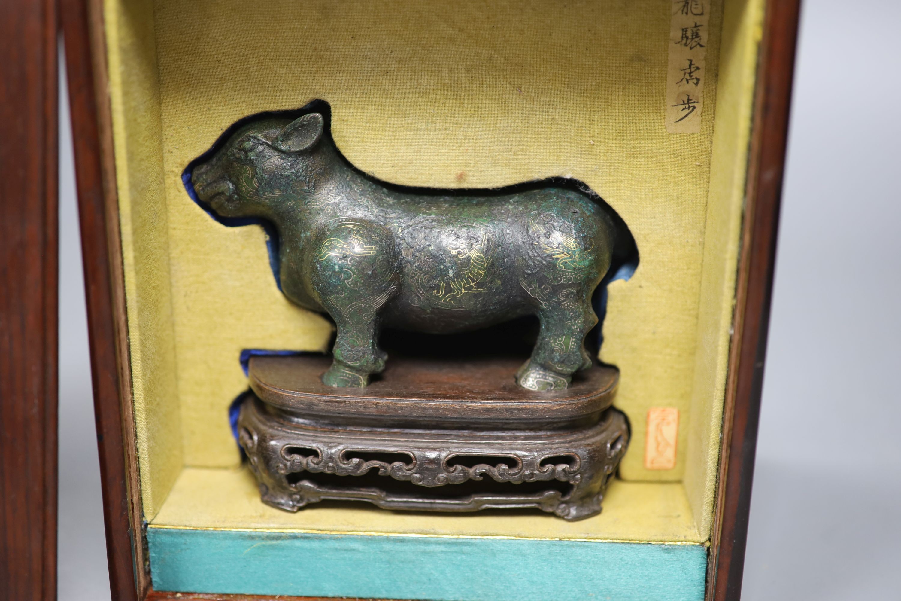 A Chinese gold and silver inlaid bronze figure of a tapir, Han dynasty or later, L. 12cm, excluding hardwood stand and fitted box